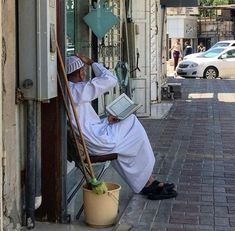 a man sitting in a chair on the side of a building holding a laptop computer