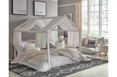 a white canopy bed sitting on top of a wooden floor