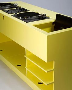 a yellow entertainment center with two turntables on it's sides and drawers