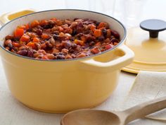 a yellow casserole dish filled with beans and carrots on a white tablecloth