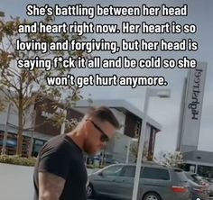 a man walking down the street in front of a building with a quote on it that reads, she's battling between her head and heart right now