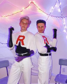 two men dressed in white are holding up their arms with the letters r on them