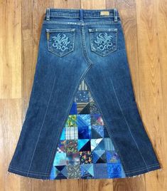 a pair of jeans with patchwork on them sitting on top of a wooden floor