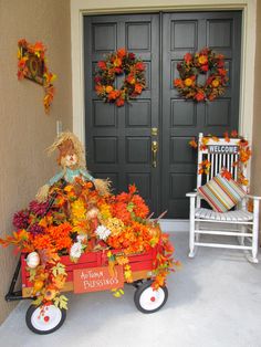 a red wagon filled with flowers sitting in front of a black door