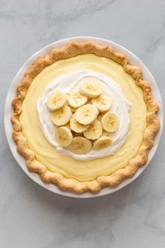 a banana cream pie on a white plate with some sliced bananas in the top crust