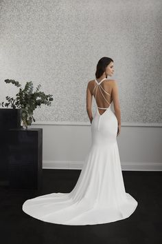 a woman in a white wedding dress standing next to a black planter and looking off into the distance