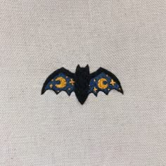 a bat embroidered onto a white shirt with yellow and blue stars on the chest pocket