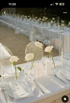 the table is set with white flowers and place settings for guests to sit down at