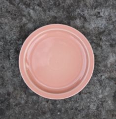 a pink plate sitting on top of a gray counter next to a knife and fork