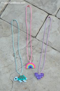 three necklaces are laying on the ground with one being a car and the other is a rainbow