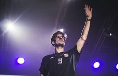 a man standing on top of a stage holding his hand up