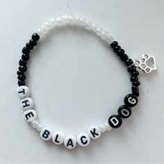 a beaded bracelet with the word black written in white beads and a silver charm