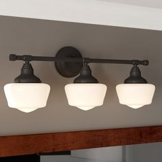 three lights are hanging on the wall above a mirror