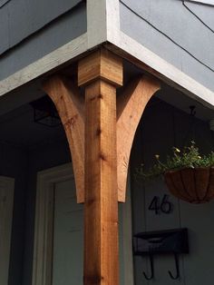 the corner of a house with a planter hanging from it's front porch