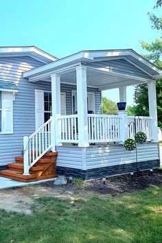 a small blue house with white porches and steps leading up to the front door