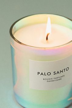 a candle with a label on it sitting in front of a gray background that says palo sano