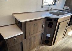 a kitchen area with sink, counter top and cupboards in a recreational vehicle or camper