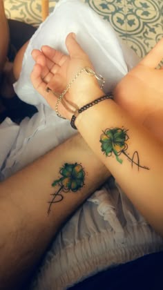 two people holding hands with tattoos on their arms and one has a shamrock tattoo on the wrist