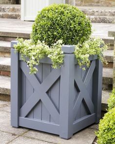 two gray planters with plants in them sitting on the steps next to some bushes