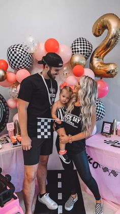 a man and woman standing next to each other in front of a table with balloons