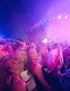 two women standing next to each other in front of a crowd at a concert with bright lights