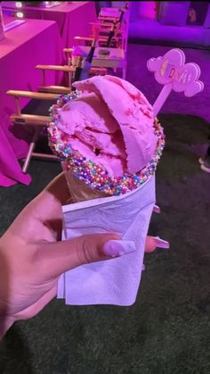 a hand holding an ice cream cone with sprinkles and decorations on it