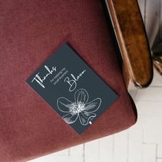 a book sitting on top of a red chair next to a wooden armrest and foot rest