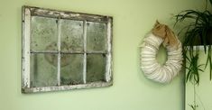 an old window is hung on the wall next to a wreath