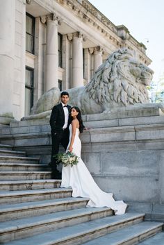 a bride and groom standing on the steps of an old building in front of a lion statue