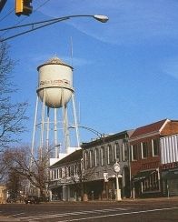 a water tower in the middle of an empty street with buildings on both sides and a traffic light above it