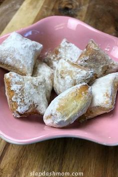 powdered sugar filled pastries in a pink plate on a wooden table with text overlay