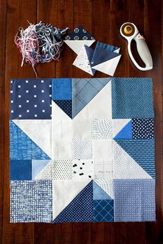 a table topped with blue and white patchwork quilts next to a pair of scissors