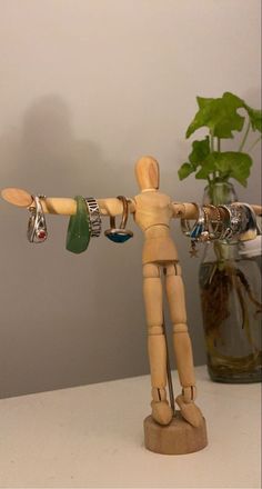 a wooden mannequin holding several rings and bracelets on it's arm