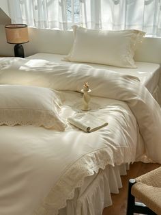 a bed with white sheets and pillows in front of a window