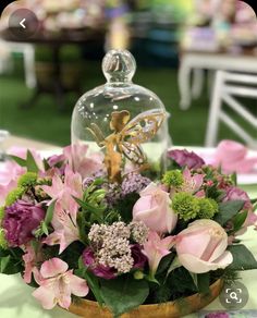 an arrangement of flowers and greenery under a glass clochet on a table