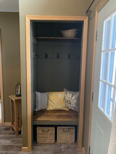 a wooden bench sitting in the middle of a room next to a door with baskets on it