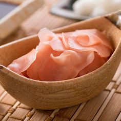 raw fish fillets in a wooden bowl with chopsticks on the table next to it