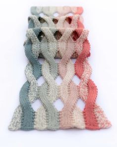 four different colors of knitted hair ties on a white surface with one knot in the middle