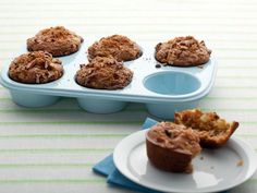 some muffins are sitting on a plate next to a cupcake tin with one bite taken out