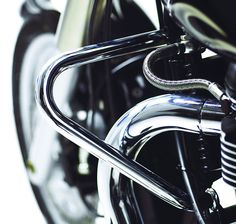 the front end of a black motorcycle with chrome trim and handlebars on it