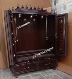 a wooden armoire with many lights on the top and bottom shelf, in front of a brick wall