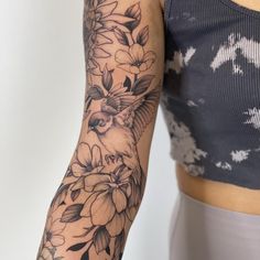 a woman's arm with flowers and a bird tattoo on her left arm is shown