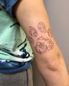 a woman's arm with tattoos on it, including flowers and skulls in the shape of hearts