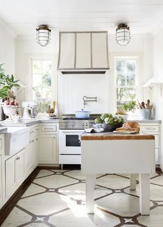 a kitchen filled with lots of white cabinets and counter top next to a stove top oven