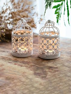 two white candles sitting on top of a wooden table