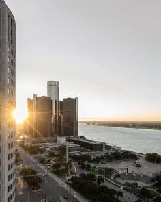 the sun shines brightly in front of some tall buildings near a body of water