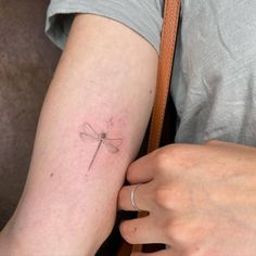 a woman's arm with a small dragonfly tattoo on it