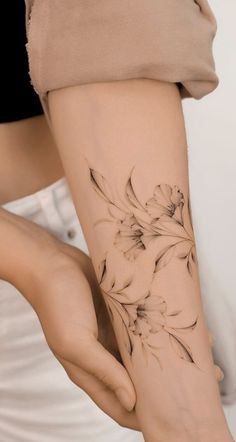 a woman's arm with flowers tattooed on it