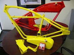 a yellow and red bike frame sitting on top of a table