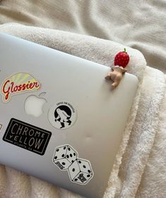 a laptop with stickers on it sitting on a blanket next to a teddy bear